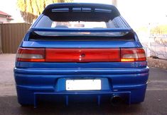 the back end of a blue car parked in a driveway