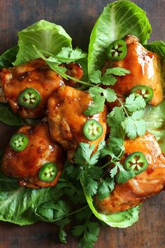 lettuce topped with chicken and green peppers on top of a wooden table,