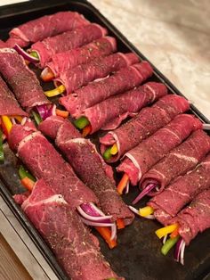 raw meats and vegetables on a baking sheet ready to be cooked in the oven