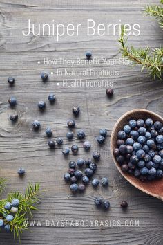 blueberries in a wooden spoon on top of a table next to pine needles and berries