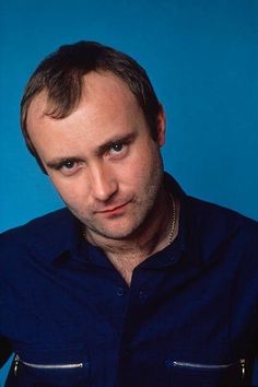 a man in a blue shirt looking at the camera with a serious look on his face