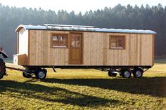 a small wooden trailer sitting on top of a lush green field