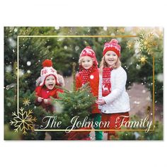 two girls in red hats and scarfs standing next to a christmas tree with snowflakes on it