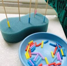 colorful toothpicks in a blue bowl on a table next to a green cushion