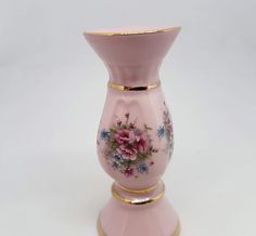 a pink vase with flowers painted on it