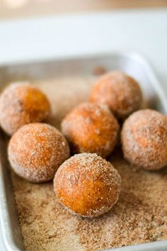 some sugared doughnuts are sitting in a pan