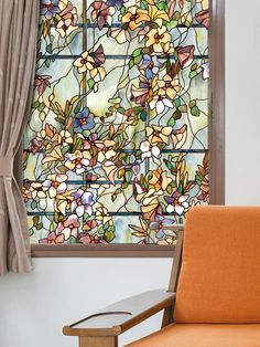 an orange chair sitting in front of a stained glass window with flowers on it's side