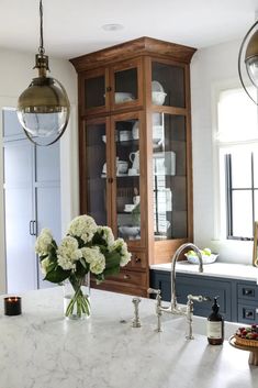 a kitchen with marble counter tops and wooden cabinetry in the center, filled with white flowers