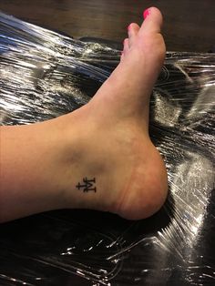 a person's foot with a cross tattoo on the side of their left leg