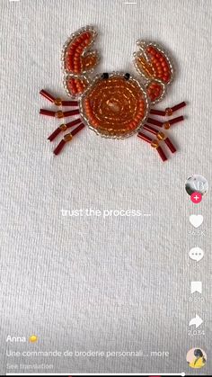 a crab made out of beads on top of a white tablecloth with red trimmings