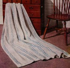 an old photo of a blanket on a dresser next to a wooden chair and table