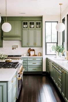 a large kitchen with green cabinets and white counter tops, along with wooden flooring