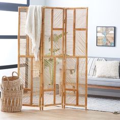 a room divider made out of bamboo with a plant in the corner and a basket on the floor