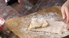 someone is kneading dough on top of a wooden table