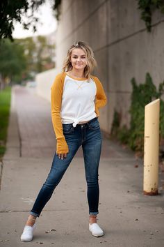 a woman posing on the sidewalk with her hands in her pockets