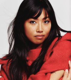 a woman with her arms crossed and wearing a red sweater, posing for the camera