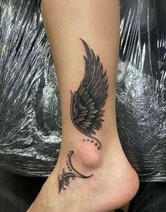 a woman's foot with an angel wing tattoo on it