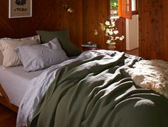 an unmade bed in a wooden room with wood paneling