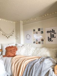 a bed with blankets and pillows on top of it in a room that has lights strung from the ceiling