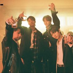 a group of young men standing next to each other holding up drinks in their hands