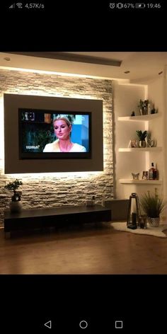 a flat screen tv mounted to the side of a stone wall in a living room