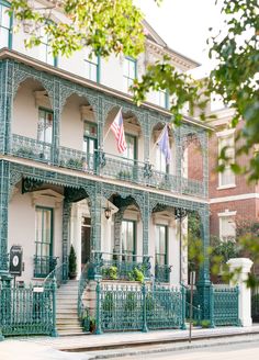 an ornate building with green railings and american flag on the second story balconies