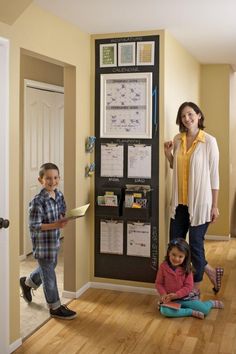 a woman and two children standing in front of a bulletin board