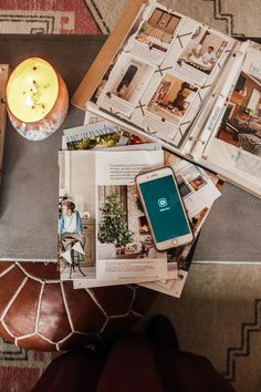 a table topped with books and magazines next to a candle on top of a rug