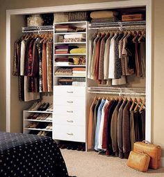 an organized closet with clothes hanging on the shelves and drawers in front of a bed