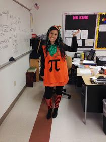 a woman dressed in an orange shirt and black tights standing in front of a whiteboard