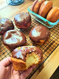 a person holding a half eaten doughnut with chocolate frosting and sprinkles