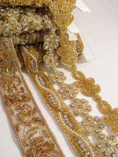 gold beaded trims are laid out on a white surface