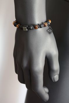 "Adjustable and trendy, you will never want to take this gemstone beaded bracelet off. Featuring a Hematite cube as its centerpiece, this beaded bracelet is made with natural 8 mm Tigers Eye and matte Black Onyx beads. This piece of mens jewelry is strung on a waxed cord and finishes off with an adjustable closure adorned with two Tigers Eye stopper beads. Hematite is said to stimulate mental activity, balance yin and yang energies and dissolve negative energies. It is considered a grounding and Two Tigers, Bracelet Christmas, Hematite Bracelet, Bracelet Mens, Bracelet Crystal, Yin And Yang, Jewelry Beaded, Gemstone Beaded Bracelets, Mens Beaded Bracelets