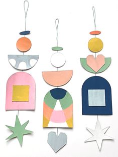 paper cut out shapes hanging from strings on a white surface with stars and circles around them