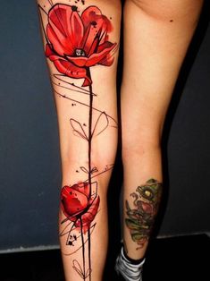 a woman's legs with tattoos on them and flowers painted on the leg area