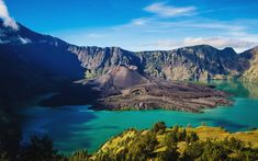 an island in the middle of a lake surrounded by mountains and trees with blue water