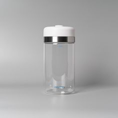 a clear glass jar with a silver lid on a gray background, the container is empty