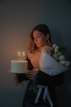 a woman holding a cake with candles on it and flowers in front of her face