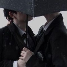 two people standing under an umbrella in the rain with their heads close to each other