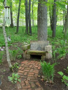 a stone bench sitting in the middle of a lush green forest filled with lots of trees