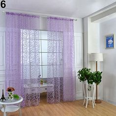 a living room with white furniture and purple sheer curtains on the windowsill, along with potted plants