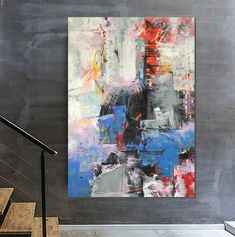 an abstract painting hangs on the wall next to a stair case and handrails