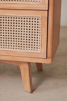 a close up of a wooden cabinet with wicker on the front and bottom drawers