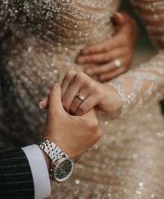 a man and woman holding hands while standing next to each other in front of glittery dresses