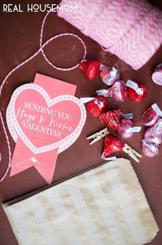 valentine's day candy on a table next to a paper bag and heart shaped lollipops