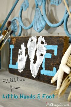 a wooden sign with the word love painted on it next to brushes and seashells