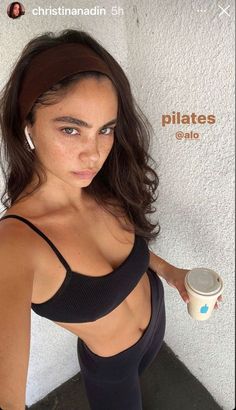 a woman holding a coffee cup in her right hand and wearing black sports bra top