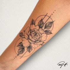 a black and white rose tattoo on the left arm with geometric circles around it, surrounded by leaves