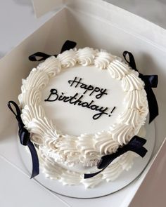 a white birthday cake in a box with the words happy birthday written on it,