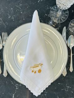 a white plate topped with a napkin next to silver utensils and wine glasses